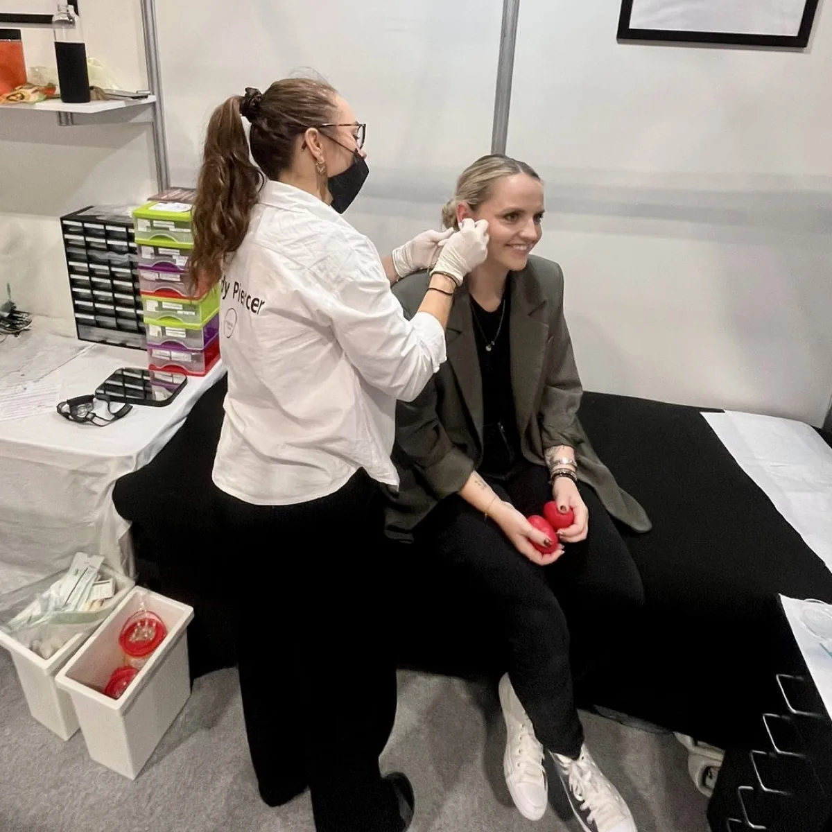 Klientka s úsměvem při piercingu na veletrhu