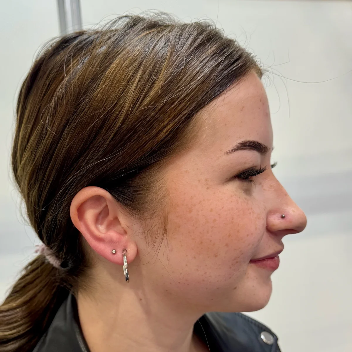Profil dívky — nose ring a ear piercings