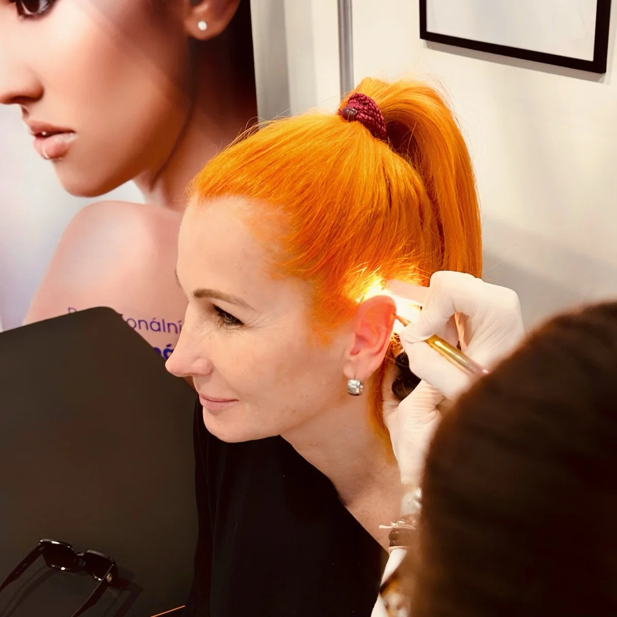 Praktická ukázka piercingu ucha na kurzu — klientka se usmívá